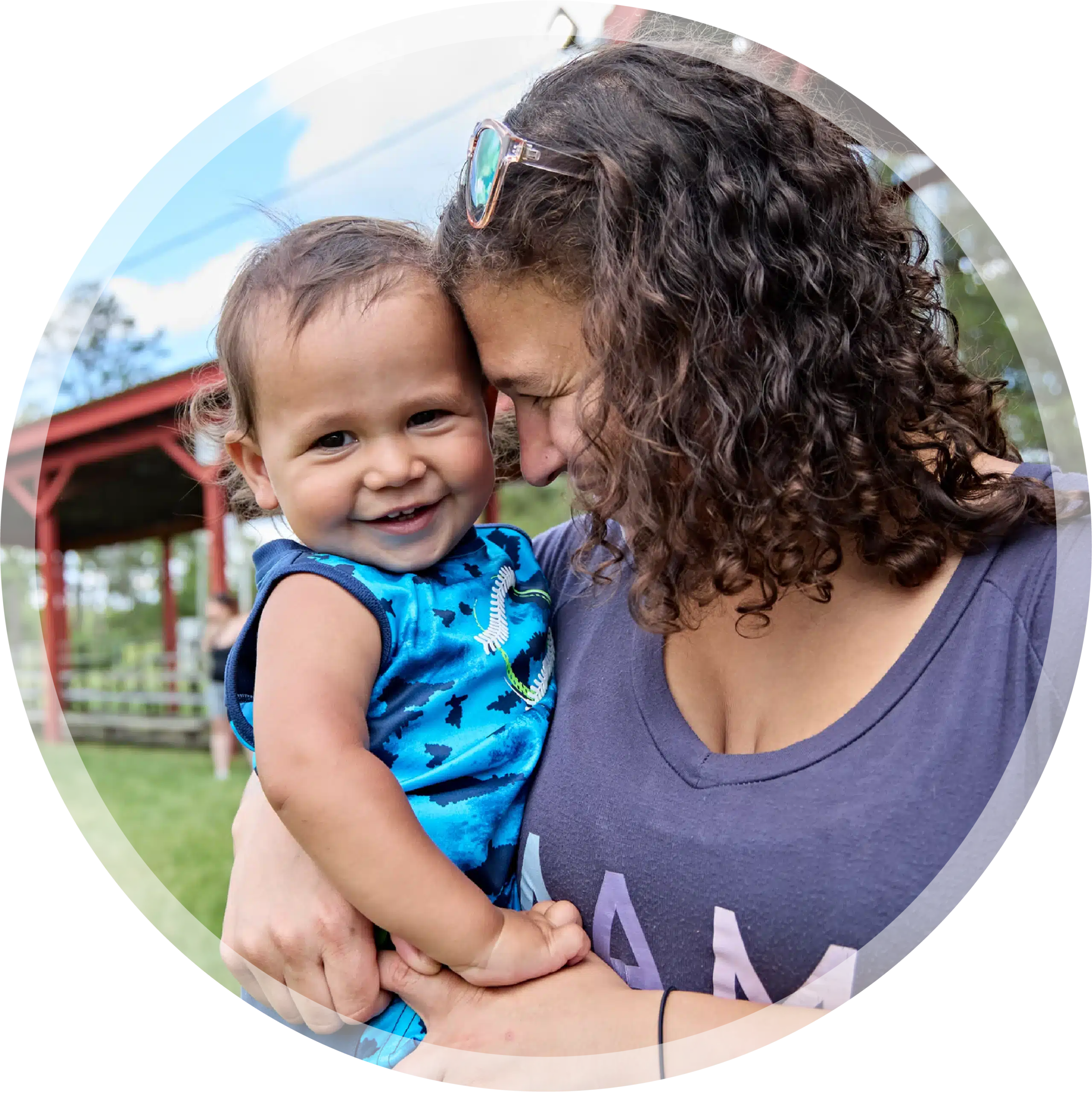 A smiling mother resting her forehand against her smiling toddler.